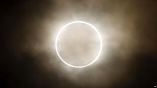 The moon slides across the sun, showing a blazing halo of light, during an annular eclipse at a waterfront park in Yokohama, near Tokyo.