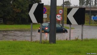 Car partly submerged in floodwater on road