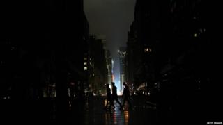 People walk on a dark New York street.
