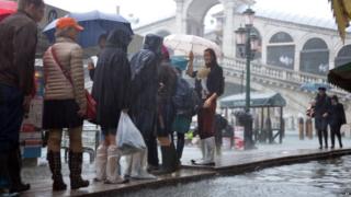 Tourists walk on footbridges near the Rialto bridge during a "acqua alta" on November 11, 2012 in Venice.
