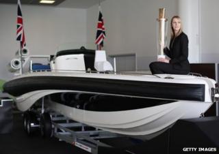 The boat David Beckham drove during the 2012 Olympic opening ceremony. A member of staff from the auction house is sat on the boat.