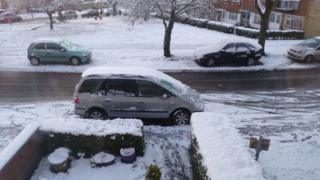 snow covers cars outside a house