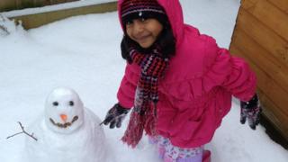 A girl shaking hands with her snowman.