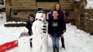 Three children next to their snowmen.