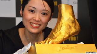 Woman poses with Golden statue of the left foot of Lionel Messi.