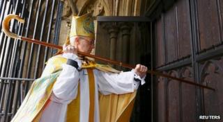Welby knocks on the door of Canterbury Cathedral with a staff