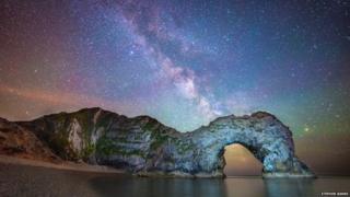 The rocks of Durdle Door frame the distant band of the Milky Way in this carefully composed shot.