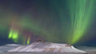 An auroral display above photographers.