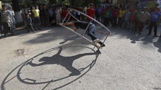 An Afghan performs acrobatics with a gym wheel at the Mobile Mini Circus For Children in Kabul