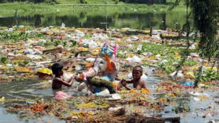 Children salvage reusable materials and offerings from a lake, a day after the immersion of idols of elephant-head Hindu God Ganesha in Bhopal, India, Thursday, Sept. 19, 2013.
