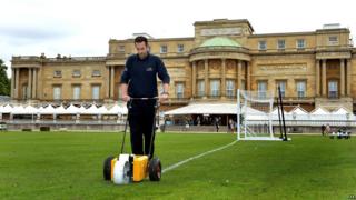 a groundsman at Wembley Stadium, marks out the the lines of a football pitch in the gardens of Buckingham Palace