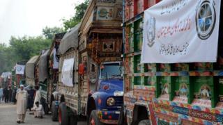 Pakistani drivers gather beside their trucks carrying earthquake relief supplies.