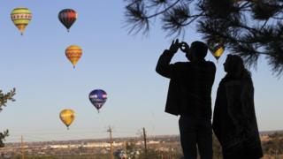 Visitors photograph balloons in the air at the 42nd Albuquerque International Balloon Fiesta.