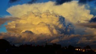 A huge yellow cloud has risen in the sky - almost bursting at the top.