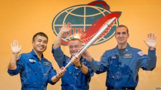 Three astronauts hold the torch for the Sochi Winter Olympics