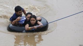 A family using an inflatable tyre tube to escape flooding.