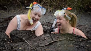 Two women laughing as they get into the bog.