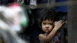 Filipino child peers outside hi house while waiting for pre-emptive evacuation at a slum area in Tondo, Manila, Philippines