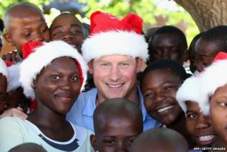 Prince Harry with children wearing Santa hats