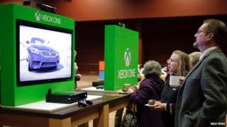 A man and woman look at an Xbox One
