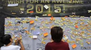 Onlookers write and post their New Year wishes on a wishing wall display at a mall in Quezon city, metro Manila 31 December 2014.