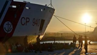 Rescued migrants wait on a dockside