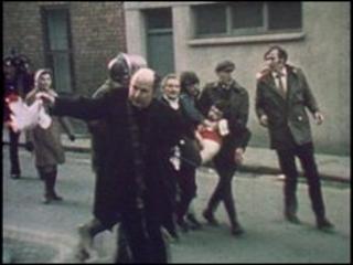 Father Daly waves a bloodstained handkerchief as he tries to lead one of the victims of Bloody Sunday, Jackie Duddy, to safety