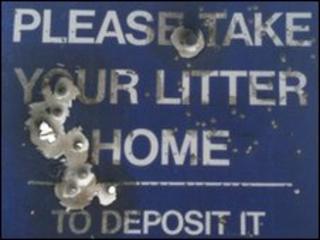 Sign apparently damaged by bullet holes