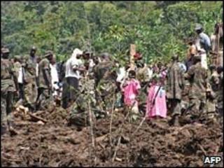 Ugandan villagers and soldiers stand on fresh earth following a landslide. Photo: 2 March 2010