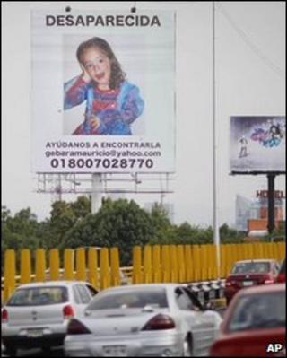 Vehicles pass a billboard with a photo of Paulette bearing an appeal to help find her
