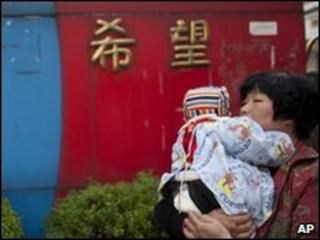 A woman holds a baby near the gate of Zhongxin Kindergarten, file pic