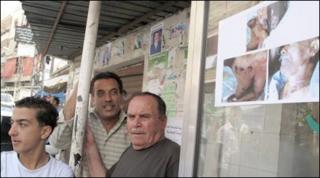 Residents of Ketermaya stand next to a poster showing the a murder victim's body
