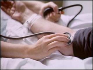 GP checking blood pressure