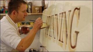 Wayne Osborne paints a sign