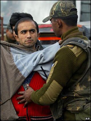 Man being searched by security forces in Indian-administered Kashmir