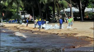 Workers clean oil on a beach in Singapore (27 May 2010)