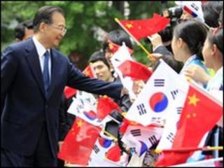 Chinese Premier Wen Jiabao (L) is greeted by children waving Chinese and South Korean flags (29 May)