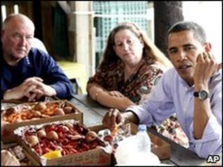President Obama is seated before boiled shrimp at a table with National Incident Commander Adm. Thad Allen and convenience store owner Patti Rigaud