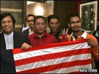 Malaysian activists pose with their national flag upon arrival in Amman