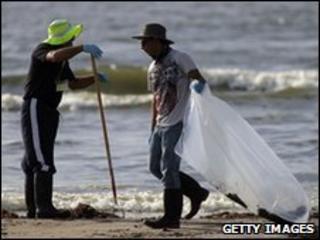 Workers hired by BP clean a beach of oil in in Grand Isle, Louisiana