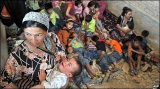 An ethnic Uzbek mother, holds her son as they wait inside of a house at the Kyrgyz-Uzbek border outside a village of Suratash
