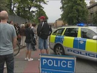 People waiting at police block on road near Cambridge railway station