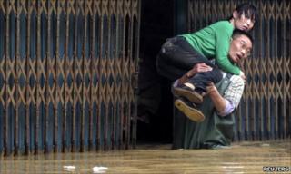 A man wades through water carrying a woman
