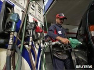An employee fills a vehicle with petrol at a fuel station in New Delhi