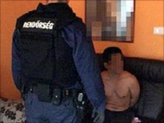 A Hungarian policeman guards a suspected illegal migrant from Vietnam