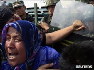 A crowd of angry locals confront security forces on a street in the city of Urumqi