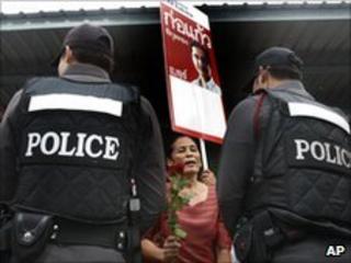 A supporter of detained red-shirt leader Kokaew Pikulthong faces police outside Bangkok district office on 28 June 2010