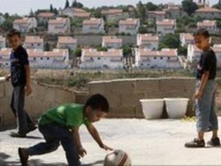Palestinian boys in the West Bank with the Jewish settlement of Halamish in the distance