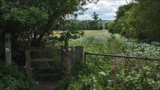 A gate and footpath through fields on the Gloucestershire Way near Winchcombe, Gloucestershire