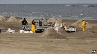 Workers clean a beach in Louisiana